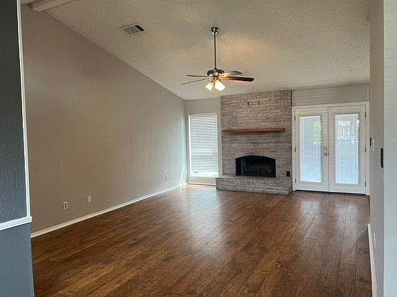view of living room with fireplace ceiling fan, vaulted ceilings, and hardwood floors
