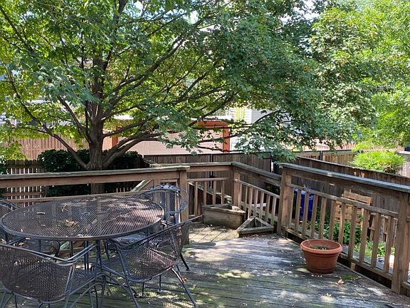 Rear deck off kitchen shaded by mature sugar maple trees. Rear yard behind deck.