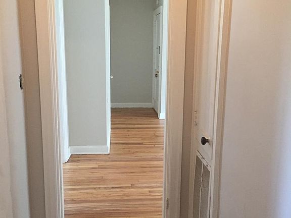 Hallway with linen closet and hardwood floors