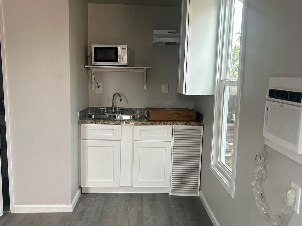 View of kitchen area with storage and cabinets, window and AC unit on wall
