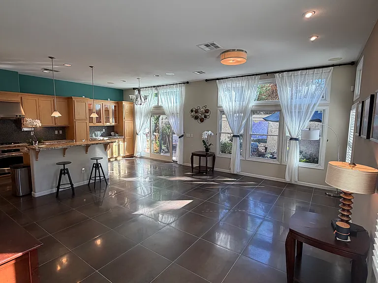 Standing at the foot of the stairs looking at the great room which contains the kitchen and living room. The high ceiling gives lots of light. Tile floors.