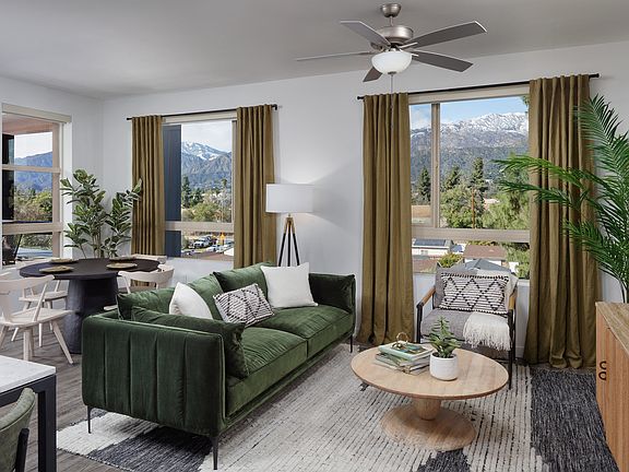 model living room with a green couch and a large window with a view of the mountains