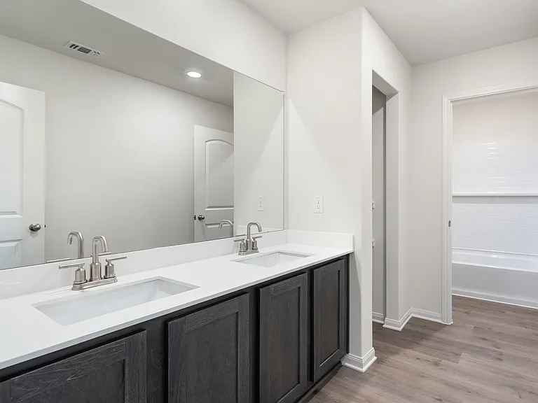 The secondary bathroom has a large vanity space and shower tub combo.