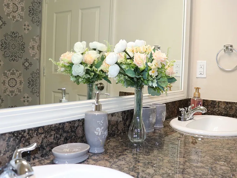Spacious vanity area with a wide mirror, granite countertop, and dual sinks for convenient shared use.