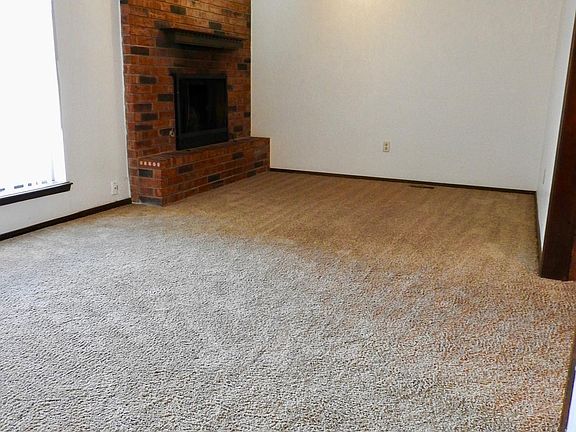 Entry and living area with wood burning fireplace. This carpet has been replaced with hardwood floors