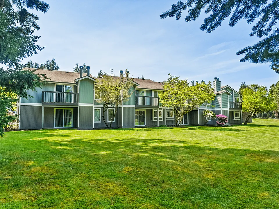 Charming apartment complex exterior with lush greenery and blooming flowers.