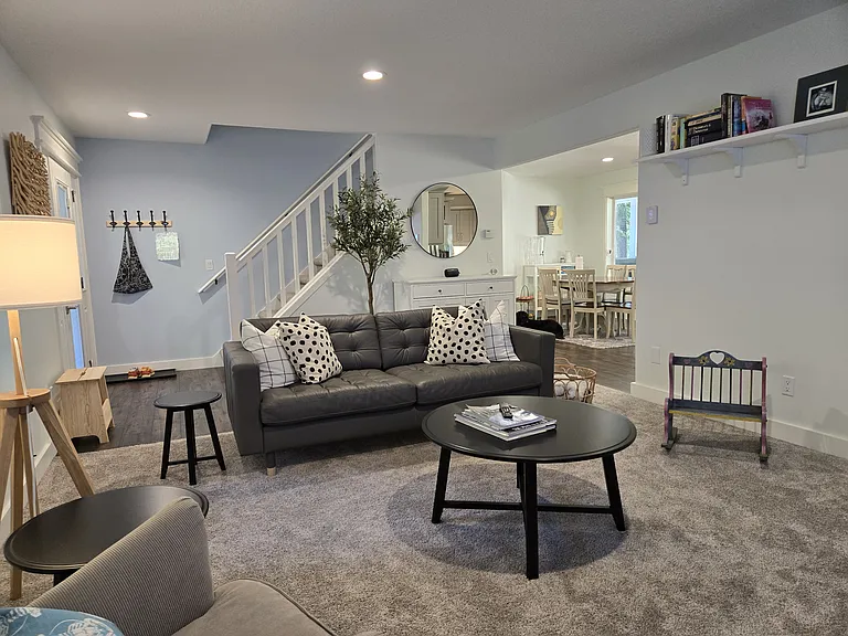 Living room featuring a couch, armchair, swinging chair, and an 85" TV