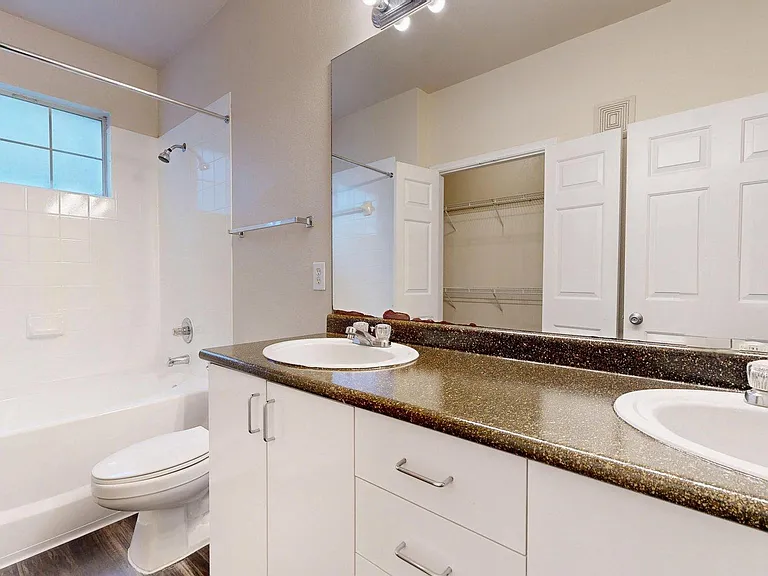 Apartment Bathroom with large soaking tub, vanity mirror and Wood-Style Flooring.