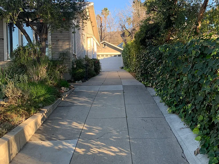 Drive way to large two car garage, small cottage house and backyard.