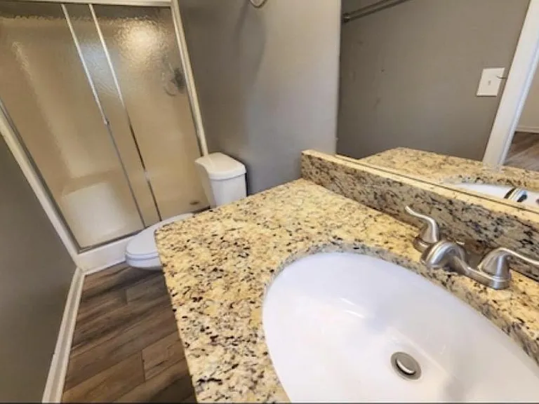 Bathroom features a granite-top vanity with large mirror, brushed-nickel fixtures, and a sliding-door shower/tub combo.