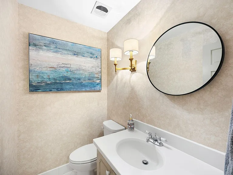 Well-appointed half bath featuring a vanity with chrome fixtures, round mirror, and updated lighting for daily convenience.