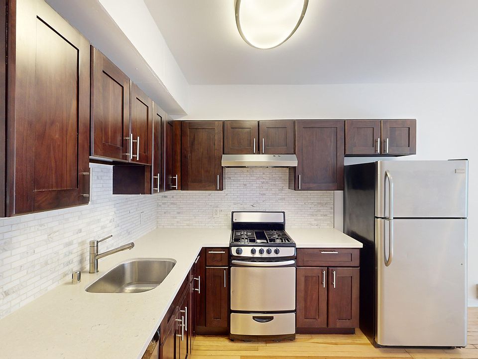 Kitchen with cabinets, refrigerator, stove, range hood, and sink