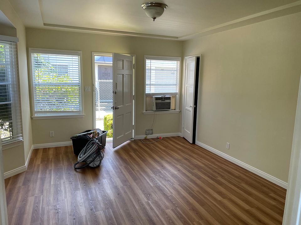 Living room with hardwood floors, AC unit, closet and security screen door.