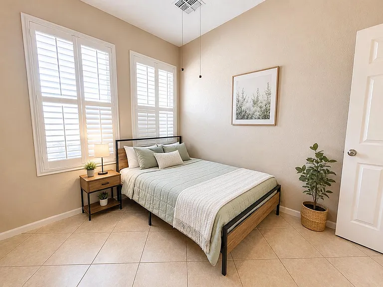 Well-appointed bedroom with plantation-shutter windows, tile flooring, and space for a nightstand and wardrobe.