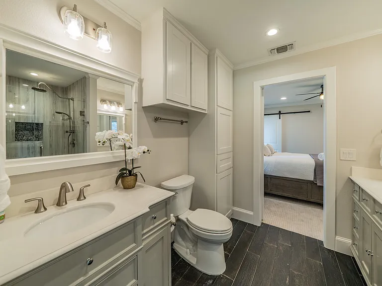 Elegant En-Suite Bath: Grey Vanity, Dark Tile Floors & Direct Bedroom Access