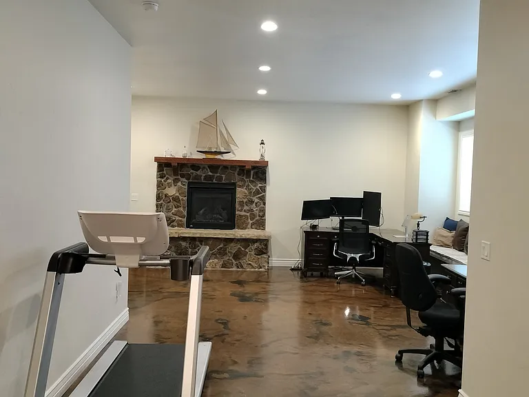 This spacious office boasts 10-foot basement ceilings, large windows for natural light, and two desks equipped with monitors and outlets for teleworking. Enjoy a treadmill for break-time exercise and a cozy fireplace to keep you comfortable.