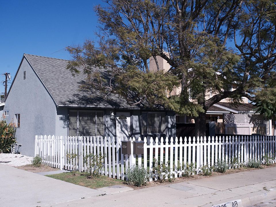 Front grassy yard with picket fence, roses, succulents and shady tree.