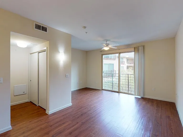 Apartment living room with wood-style flooring with balcony or patio in select homes.