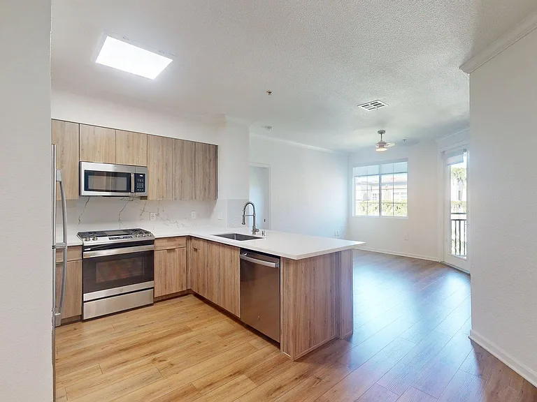 Apartment Kitchen with Stainless Steel Appliances, white countertops and wood-style flooring