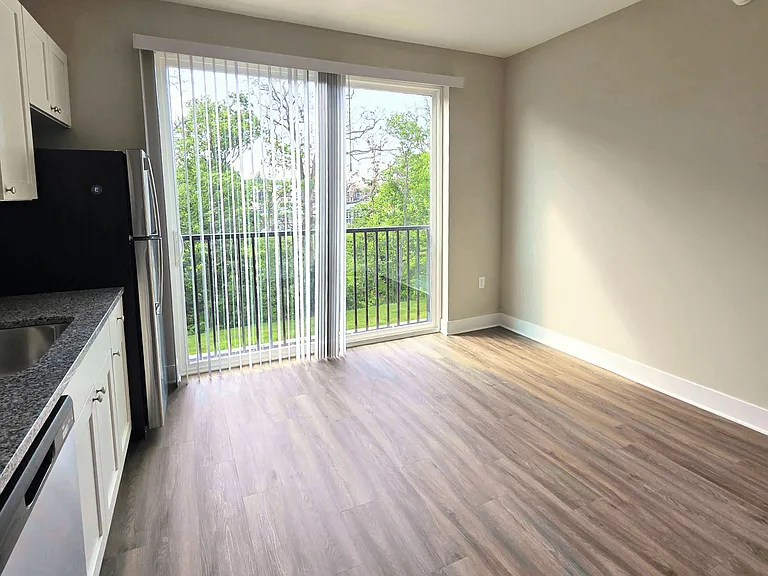 Kitchen and living area with balcony of an available apartment unit at Greenwood Commons Apartments in Delaware, OH.