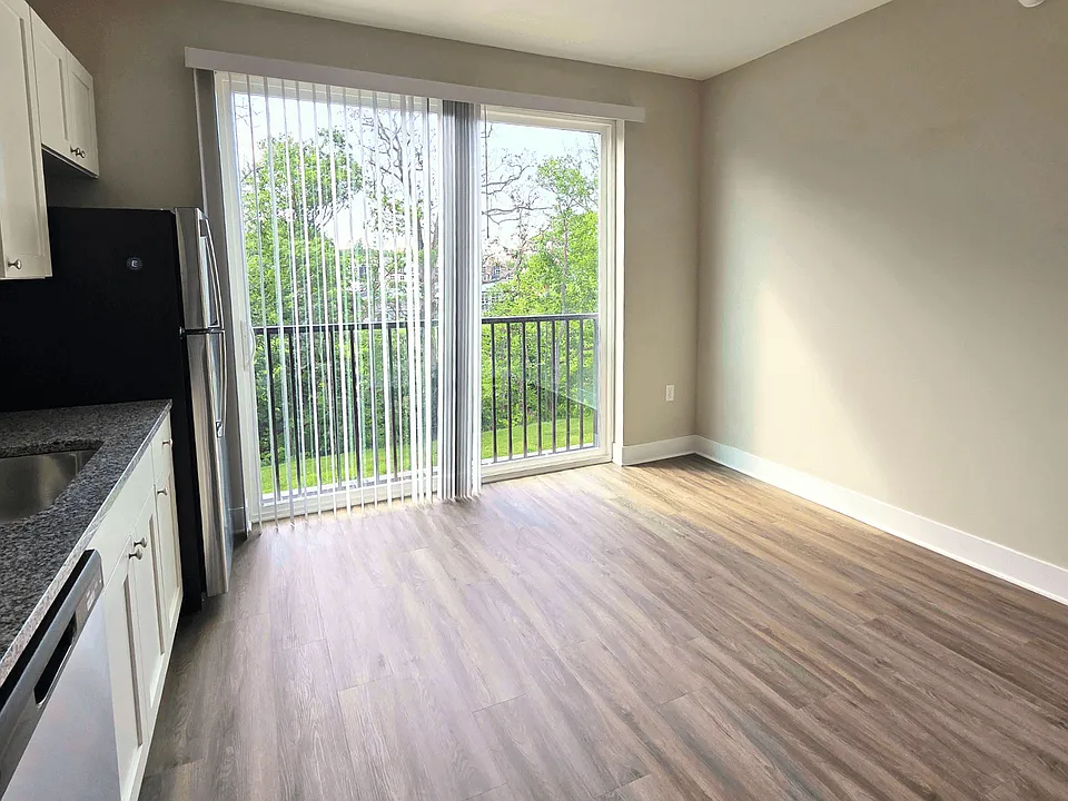 Kitchen and living area with balcony of an available apartment unit at Greenwood Commons Apartments in Delaware, OH.