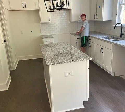 Kitchen with granite countertops, backsplash and island. The builder will install stainless steel dishwasher and smooth electric cooktop/oven. The owner will install a refrigerator