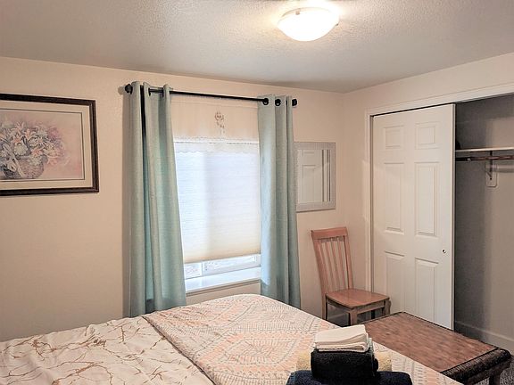 The room has large window with shade and curtains, and a large closet with a mirror right outside it to help you dress