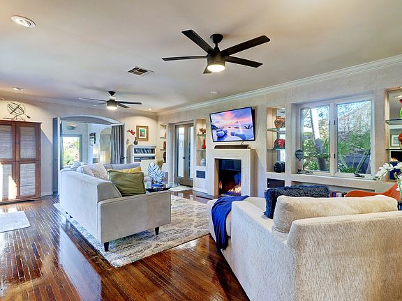 Living room with fireplace and views toward sunroom and both patios.