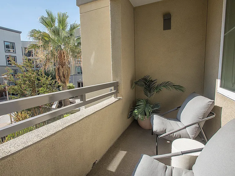 Private balcony with comfortable seating and scenic views of greenery and blue skies.