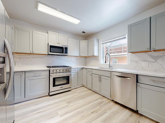 Renovated kitchen with lots of cabinetry, gas range, over-the-oven microwave, refrigerator with icemaker, and quiet dishwasher.