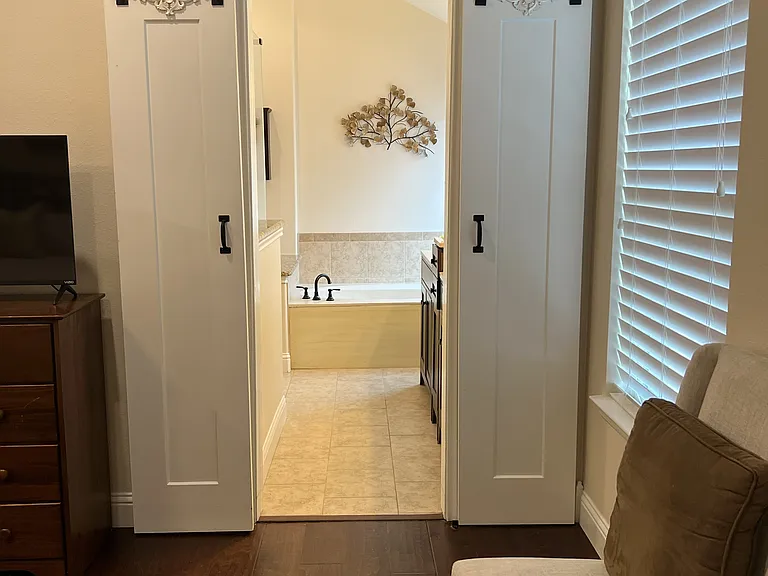 Stylish barn-style sliding doors leading into the luxurious primary bathroom suite.