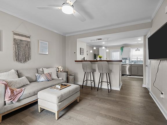 The open concept let's the natural light flood in when blackout shades are not drawn. The kitchen and dining area are just beyond the large island with tall stools.