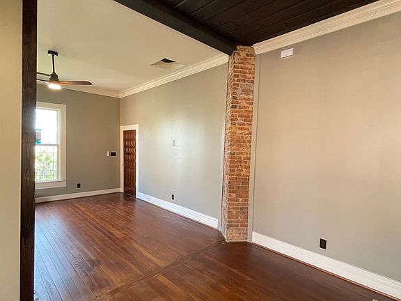 large living space, stained wood floors, original brick column