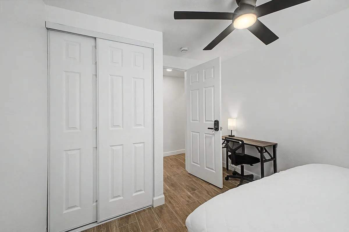 Bedroom with a sliding-door closet, ceiling fan with light, and a dedicated desk area for working or studying. - W 6th Dr