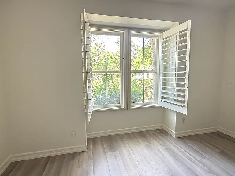 Abundant natural light with beautiful plantation shutters and a peaceful green view.