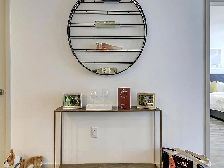 Entry Table With Decorative Books, Glasses, and Framed Photos Beneath Circular Wall Shelving