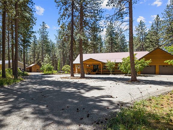 Freshly graveled driveway leads to the ranch style home, shop/barn and original barn.