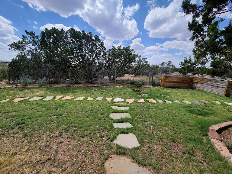 Landscaped fenced backyard with wild grasses facing southern-facing open spaces.