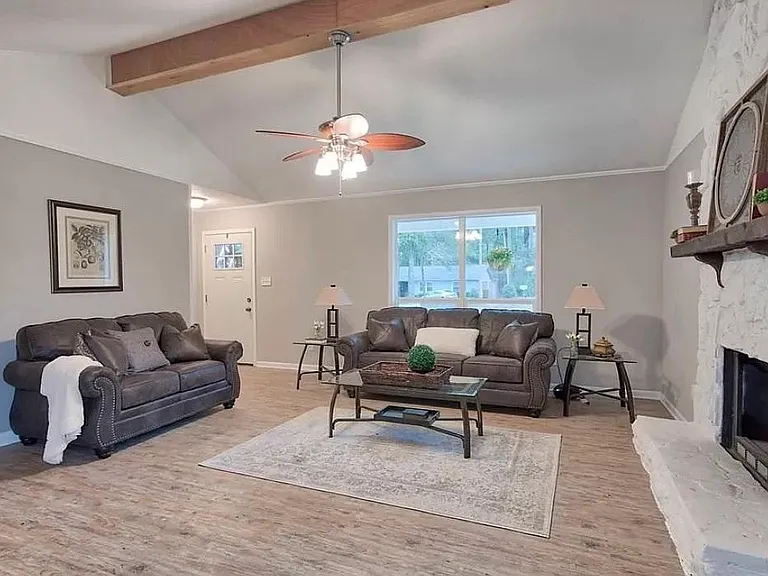 Living room boasting wood burning fireplace and wood beam ceiling