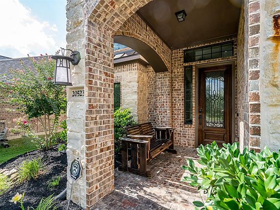 A picture perfect spot to sit and have your morning coffee! This covered front porch surrounded by brick and stone, blooming foliage and a pretty wrought iron door welcomes you to enter the home!