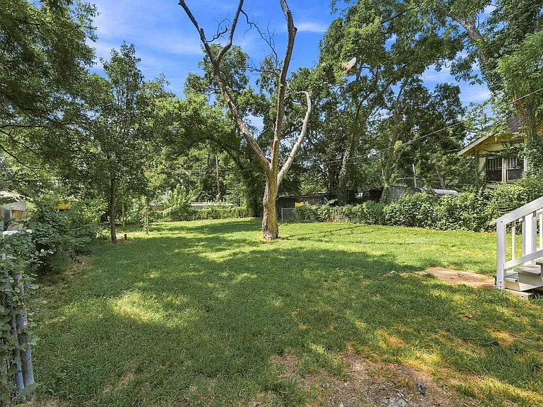 Expansive green lawn with mature trees and perimeter fencing