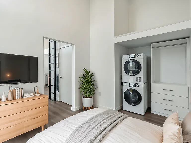 Convenient bedroom with a bed, dresser, and washer-dryer unit at Alt Capitol Hill.