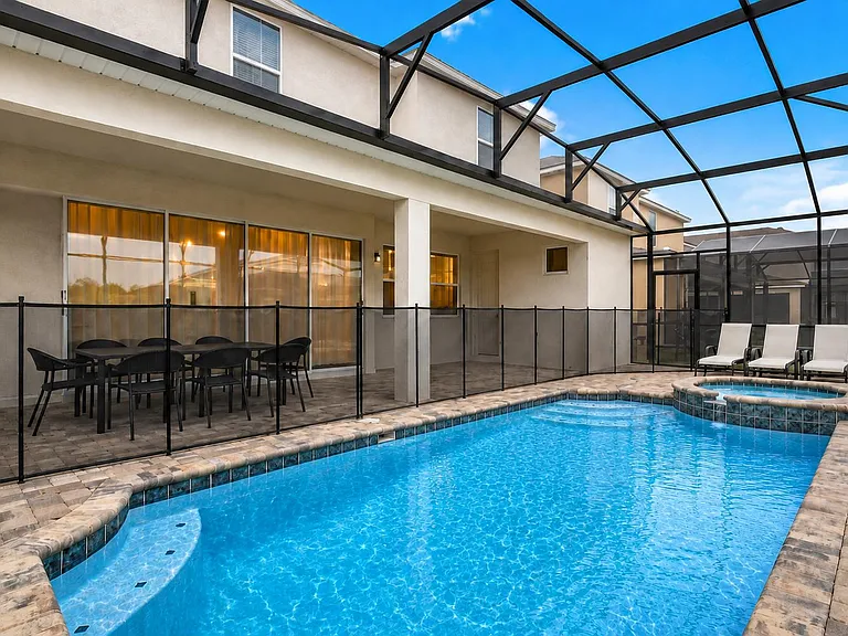 Screened-in backyard patio with in-ground pool, safety fencing, and space for outdoor dining and lounge seating.