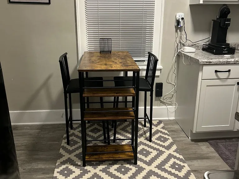 Small kitchen table in the kitchn that is located new a small pantry.