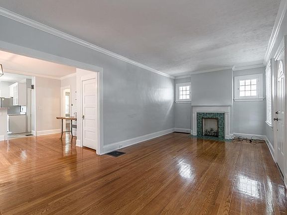 Living room features hardwood floors, crown molding, plenty of windows for natural light, and a ceramic inoperable fireplace