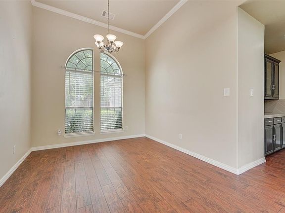 Empty room featuring dark wood finished floors, a chandelier, and ornamental molding