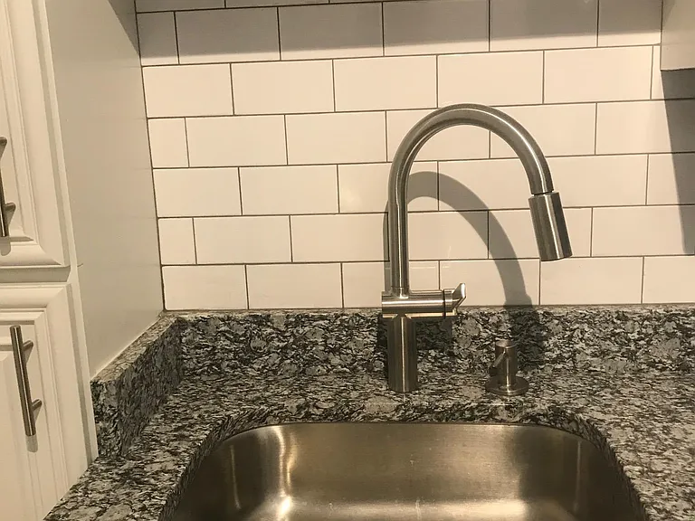Granite countertops with stainless sink and fixtures, subway tile backsplash.