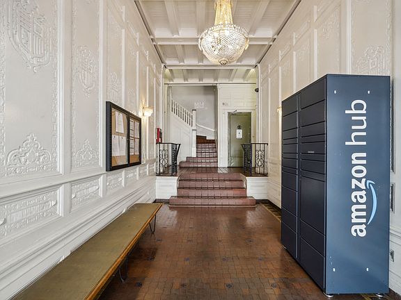Hallway with ornate walls, terracotta tiles, chandelier, bench, stairs, Amazon Hub locker