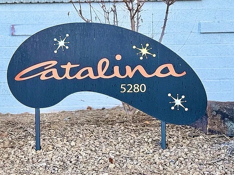 Chic and inviting apartment sign reading 'Catalina 5280' with decorative graphic accents, set amidst a serene stone landscape.