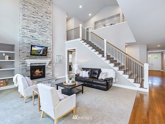 Impressive family room with soaring ceiling and a dramatic floor to ceiling stone-wrapped fireplace.